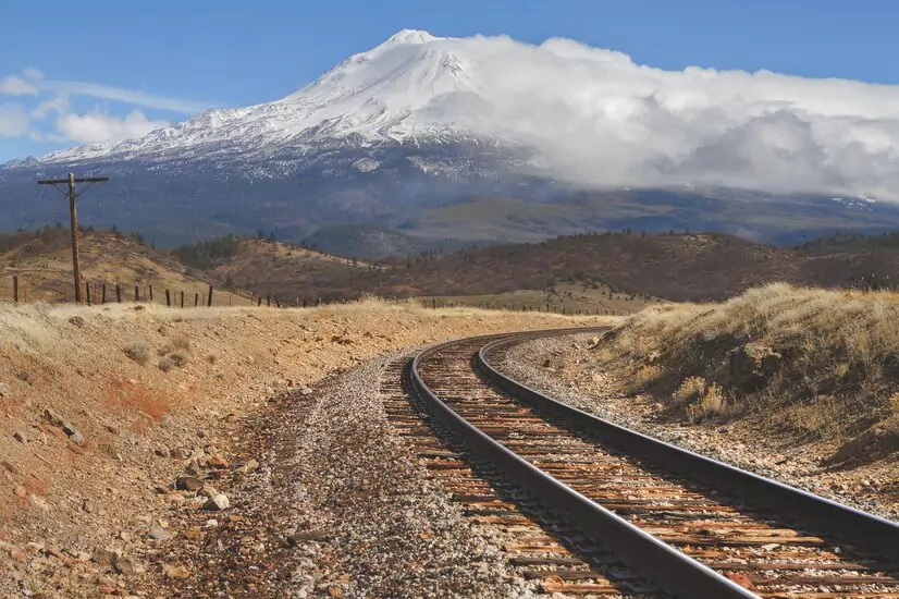 train-tracks-middle-empty-field-with-snowy-mountain-distance